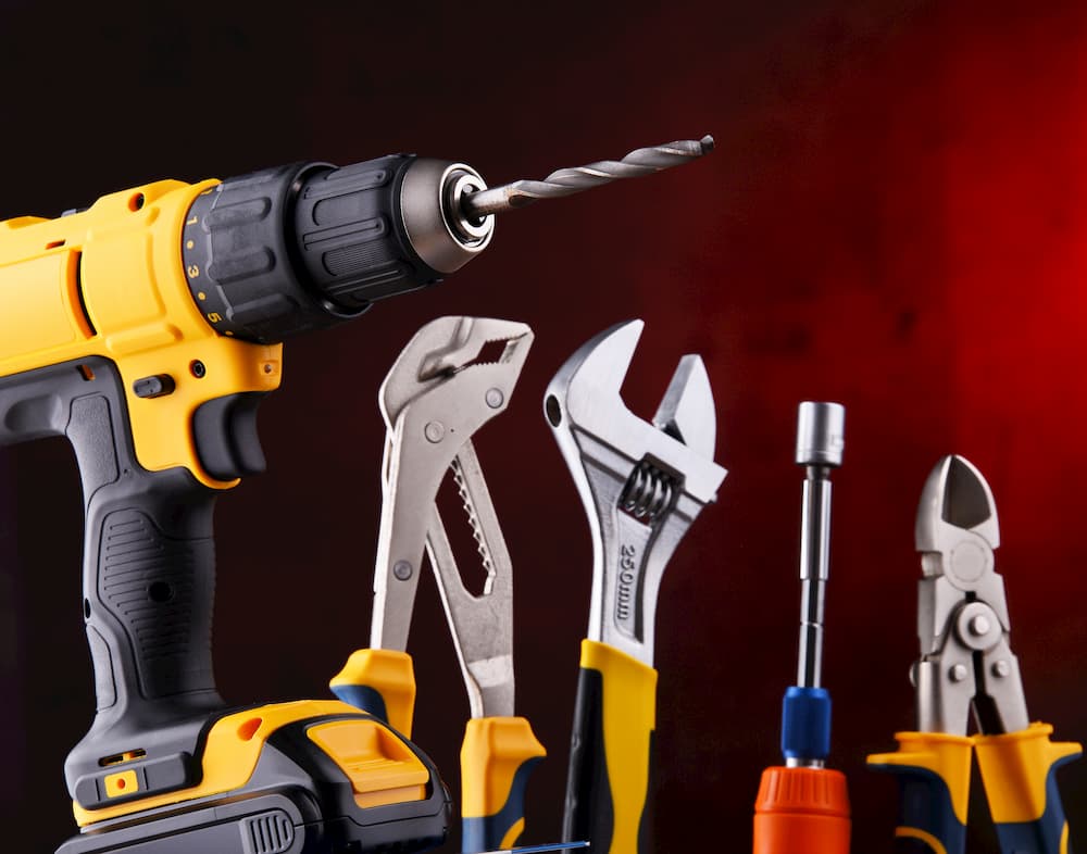 Composition with different kinds of hardware tools including cordless drill, monkey spanner and screwdriver