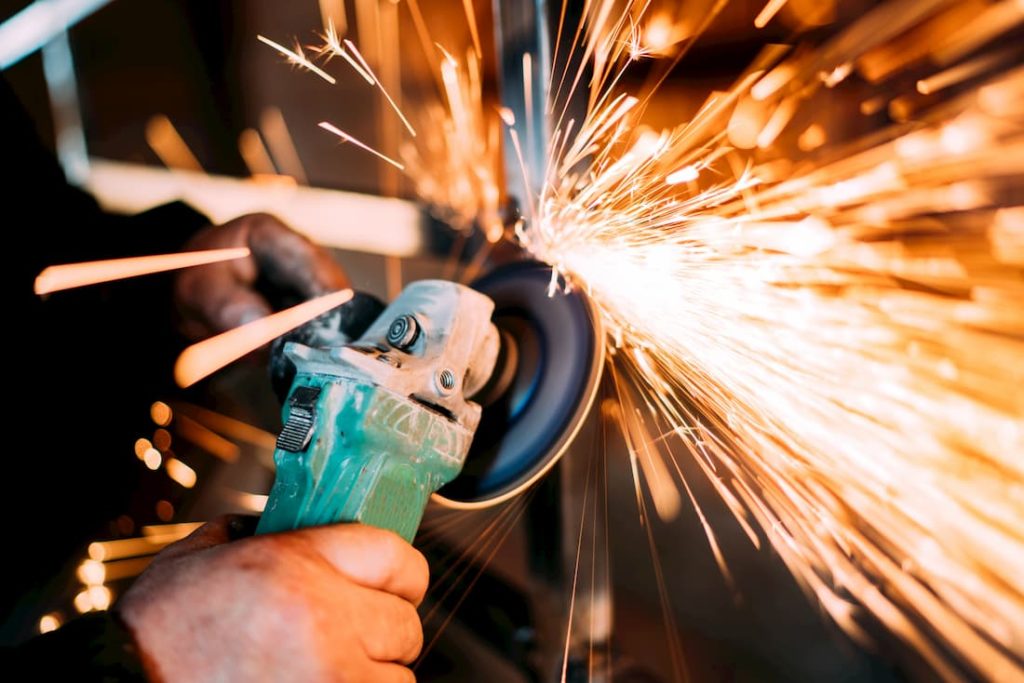 man using electric handheld grinder creating sparks