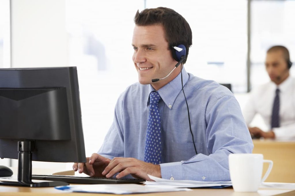 smiling happy customer service employee at desk working on computer