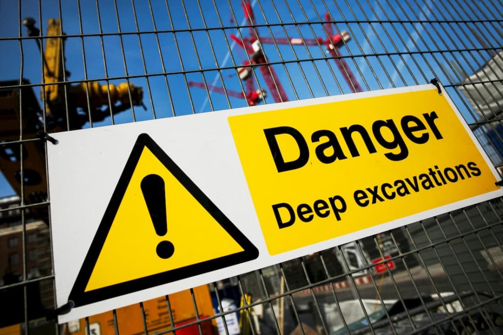 danger safety sign fastened to a metal work site fence